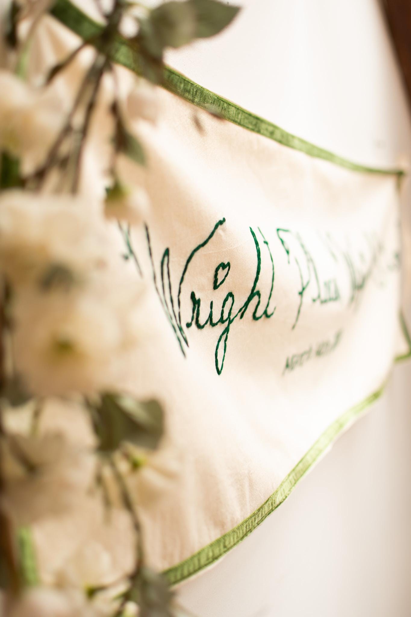 Close-up of a white pillow with green text and floral patterns.